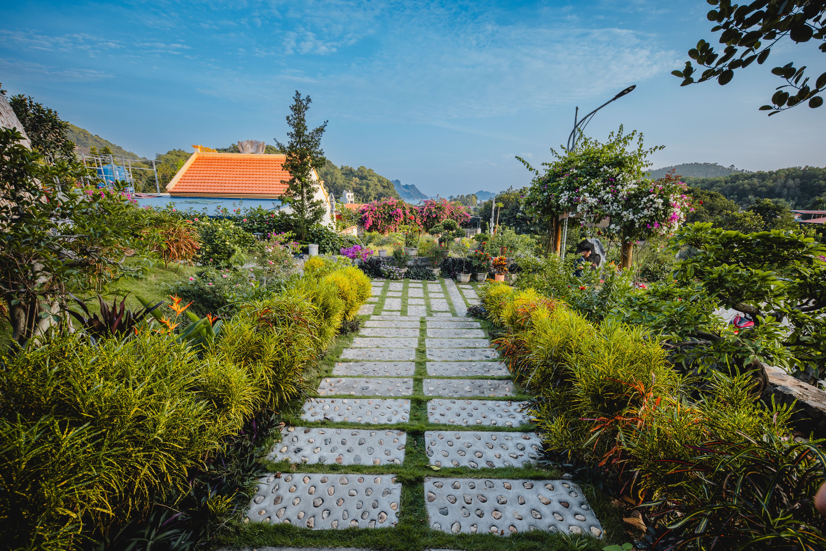 A garden pathway leading to a building with a red roof.