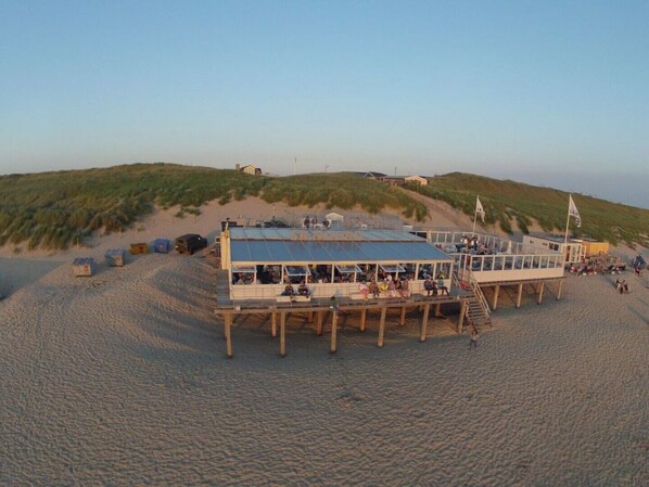 A beachside building with a covered deck and a flag.
