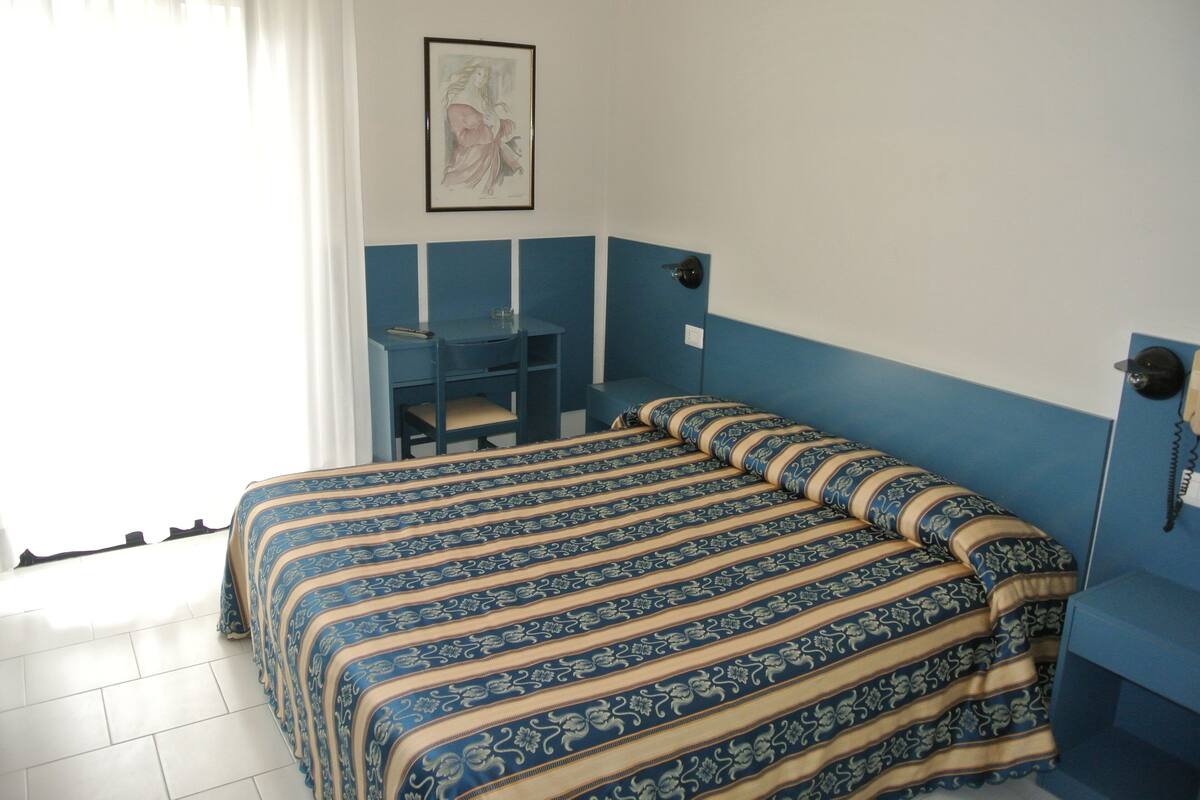 Een kamer met een bed, een bureau en een stoel.