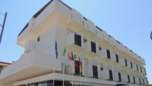 Un hôtel à plusieurs étages, doté de balcons, d’une enseigne indiquant « PRINCIDE » et de plusieurs drapeaux.