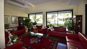 Un vaste espace de vie agrémenté de canapés rouges, d’une table basse et de grandes fenêtres offrant une vue sur l’extérieur.