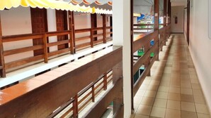 A corridor with wooden benches and a tiled floor, leading to a room with a view of a building outside. - Hotel Turistico de Alagoinhas (Alagoinhas)