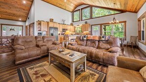 A spacious living room with leather sofas, a wooden coffee table, and a large window overlooking a lush garden. - A Mornings Mist - Morganton, GA (Morganton)