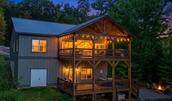 Eine zweistöckige Holzhütte mit Balkon, Terrasse und Feuerstelle.