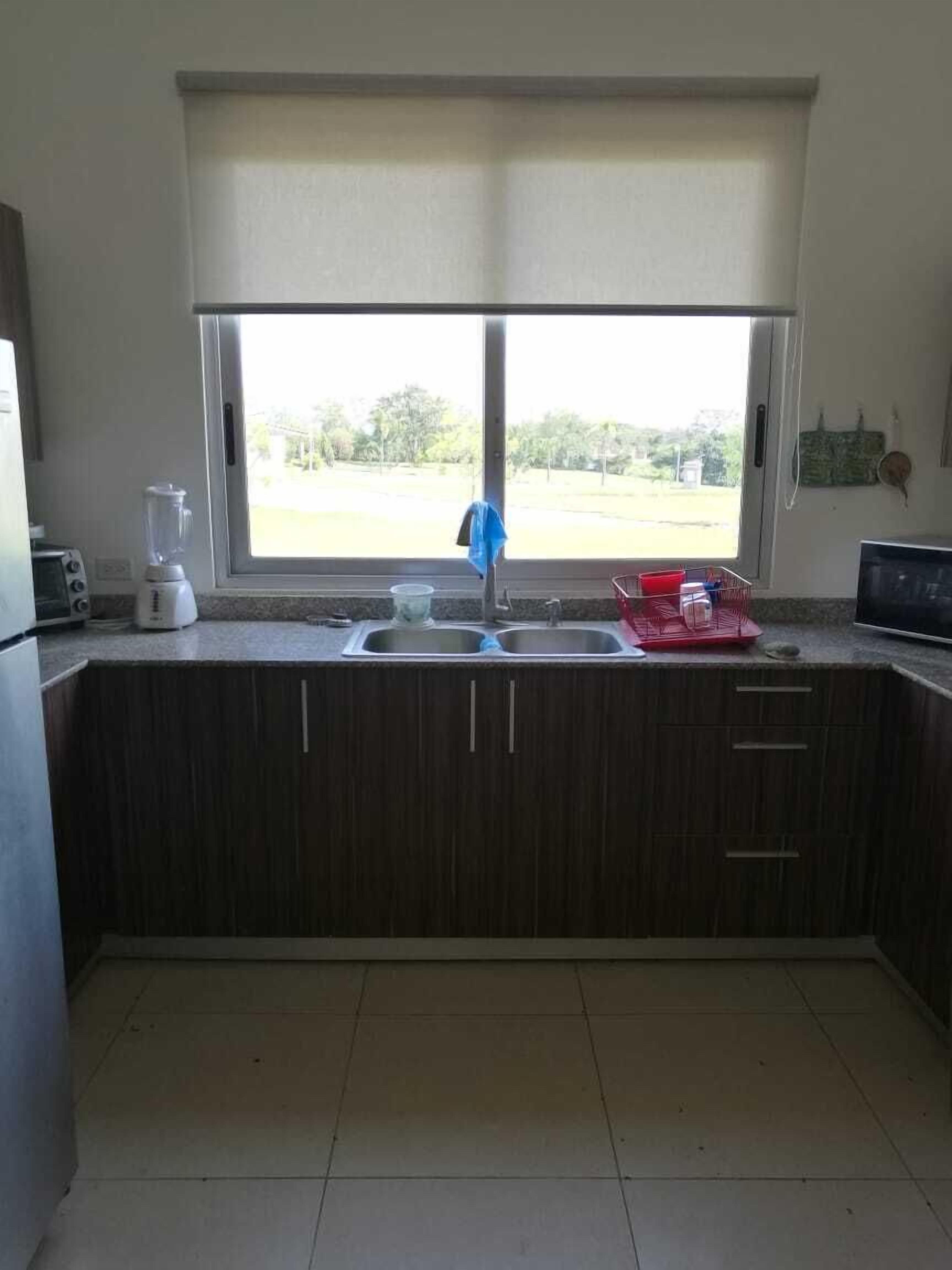A kitchen with a window, a sink, a blender, and a toaster.