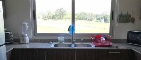A kitchen with a window, a sink, a blender, and a toaster.