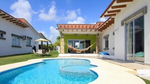 A swimming pool with a hammock, a covered patio, and a house with a tiled roof. - Beach house in Panama city Punta Barco Viejo (Panamá)