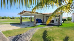 A modern house with a covered patio, a swimming pool, and a well-maintained lawn. - Beach house in Panama city Punta Barco Viejo (Panamá)