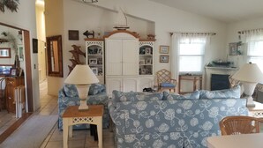 Een gezellige woonkamer met een bank, twee bijzettafels met lampen, een houten kast met decoratieve objecten en een open haard.