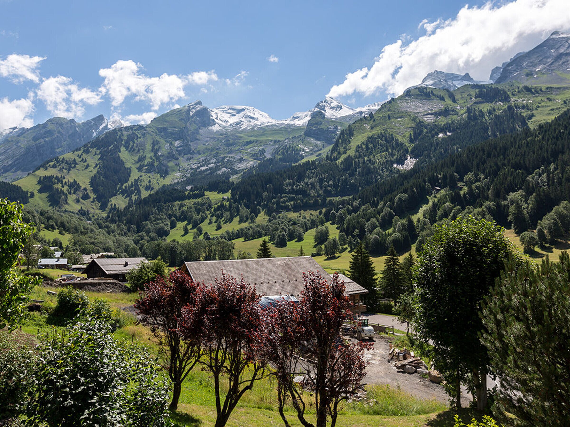 A mountain landscape with a house and a small building in the foreground.