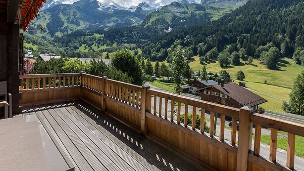 A wooden deck with a view of a mountainous landscape.