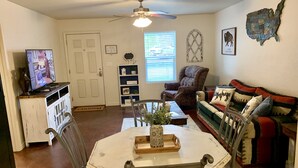 A living room with a dining table, chairs, a sofa, a TV, a ceiling fan, and a decorative wall piece. - Unique space on WTAMU campus. Walk to anything and everything! (Canyon)