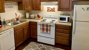 A kitchen with wooden cabinets, a stove, a sink, and a microwave. - Unique space on WTAMU campus. Walk to anything and everything! (Canyon)