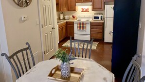 A kitchen with wooden cabinets, a white stove, a microwave, and a refrigerator. There is a sign that says "Eat" above the stove. - Unique space on WTAMU campus. Walk to anything and everything! (Canyon)