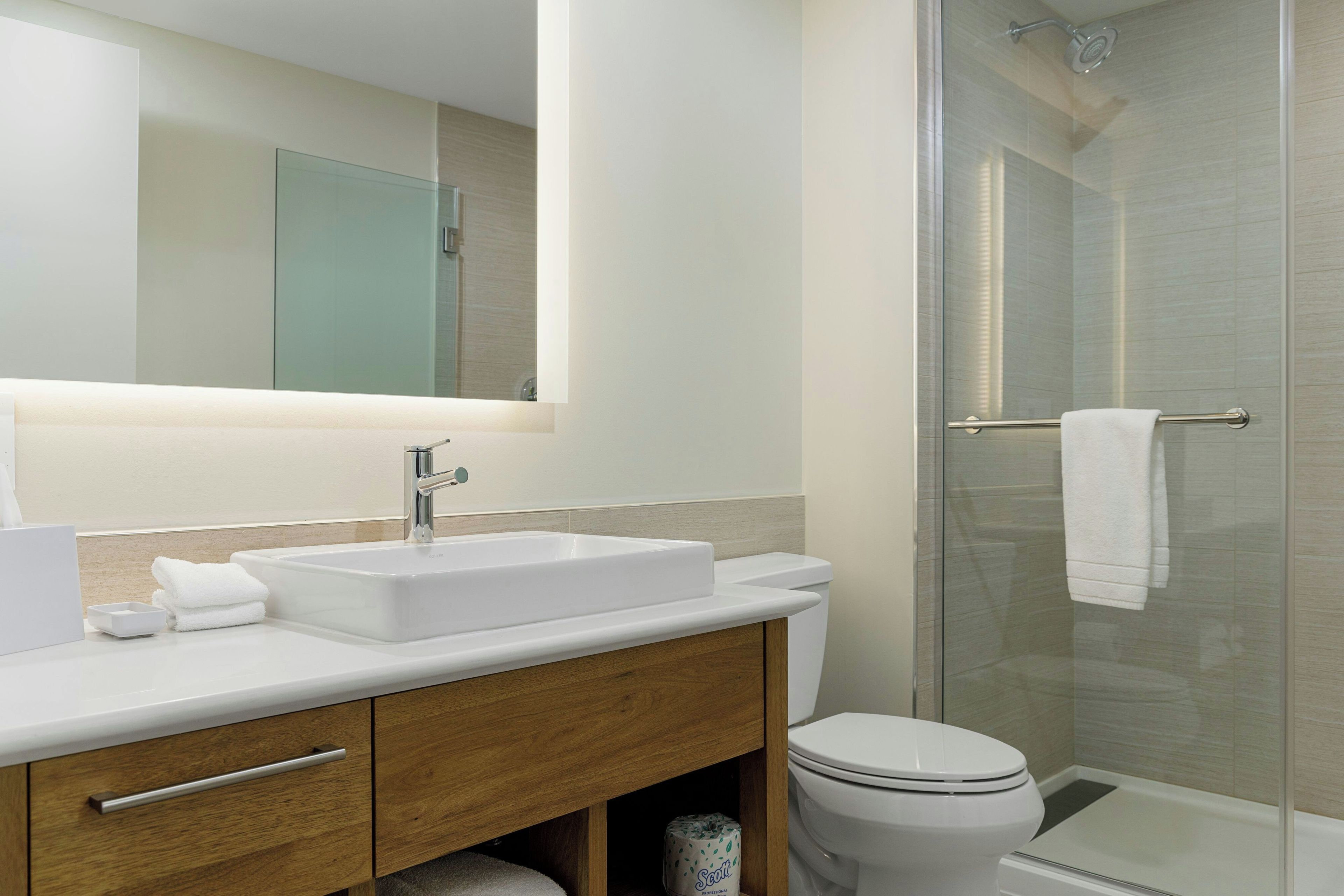 Une salle de bain moderne avec un lavabo blanc, un miroir et des toilettes.
