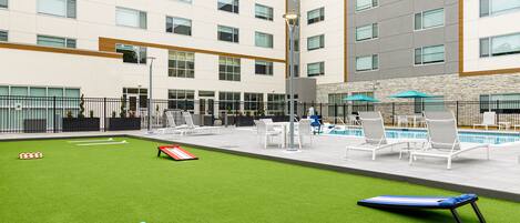 A courtyard with a pool, outdoor seating, and a billiards table.