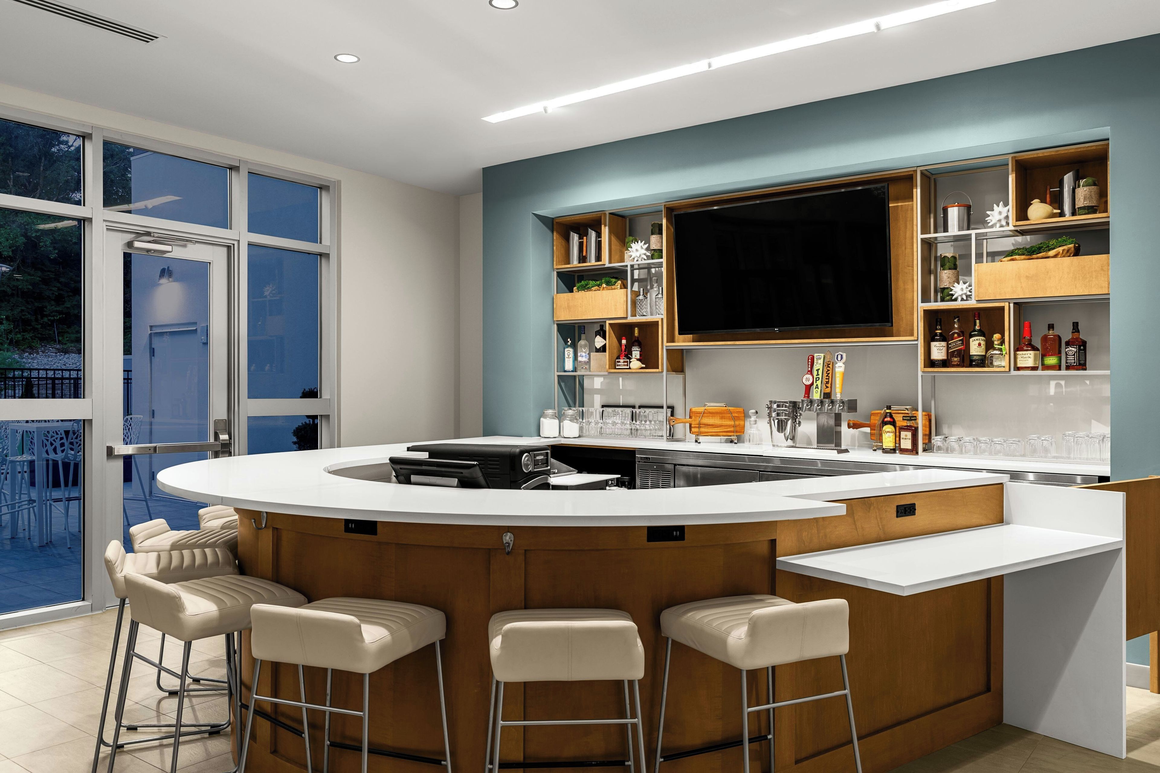 A modern kitchen with a central island, bar stools, and a built-in TV.