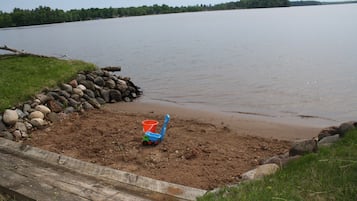 Enjoy a serene lakeside retreat with a dock leading to a sandy area, perfect for relaxation and play.