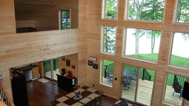 A spacious cabin with a dining area, kitchen, and large windows offering views of the outdoors. - Paradise Shores & Fish Galore ~your own private beach & dock! (Cable)