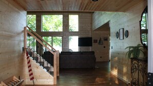 A spacious wooden interior with a staircase, a sofa, and a television. - Paradise Shores & Fish Galore ~your own private beach & dock! (Cable)