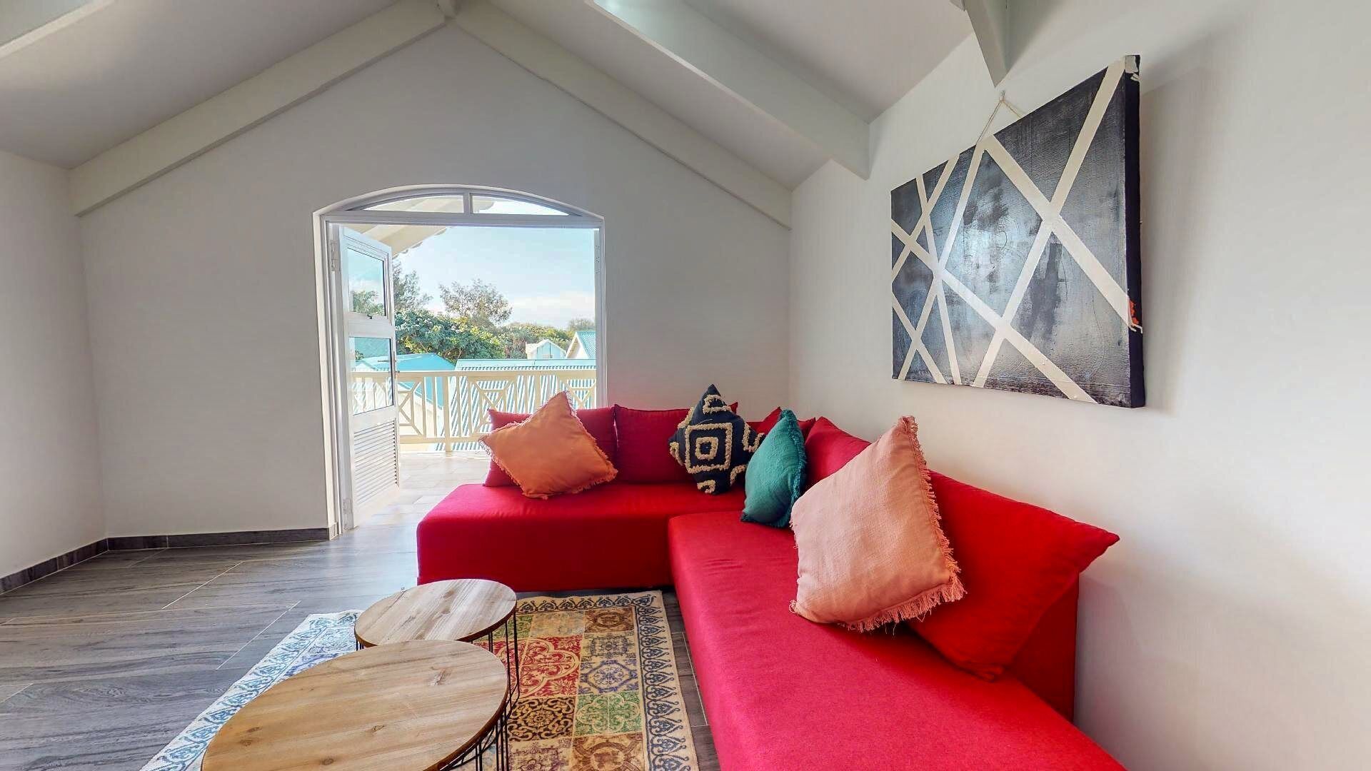 A cozy room with a red sofa, a patterned rug, and a wooden table.