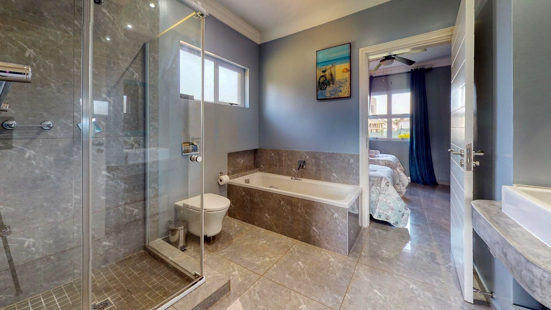 A modern bathroom with a glass shower enclosure, a bathtub, and a toilet.