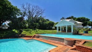 A swimming pool with a brick deck and a covered pavilion. - Caribbean Estate Deluxe (Port Edward)