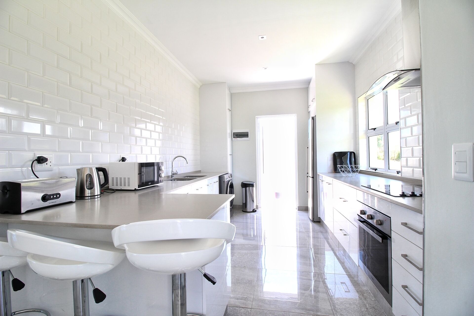 A modern kitchen with white subway tiles, stainless steel appliances, and a central island with bar stools.