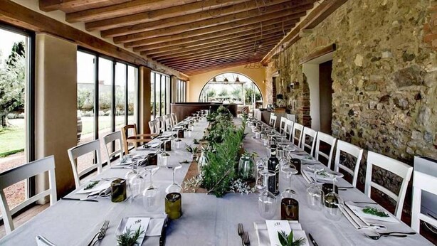 A long dining table set for a meal in a rustic room with stone walls and wooden beams. - Locanda dell'Aioncino (Bibbona)
