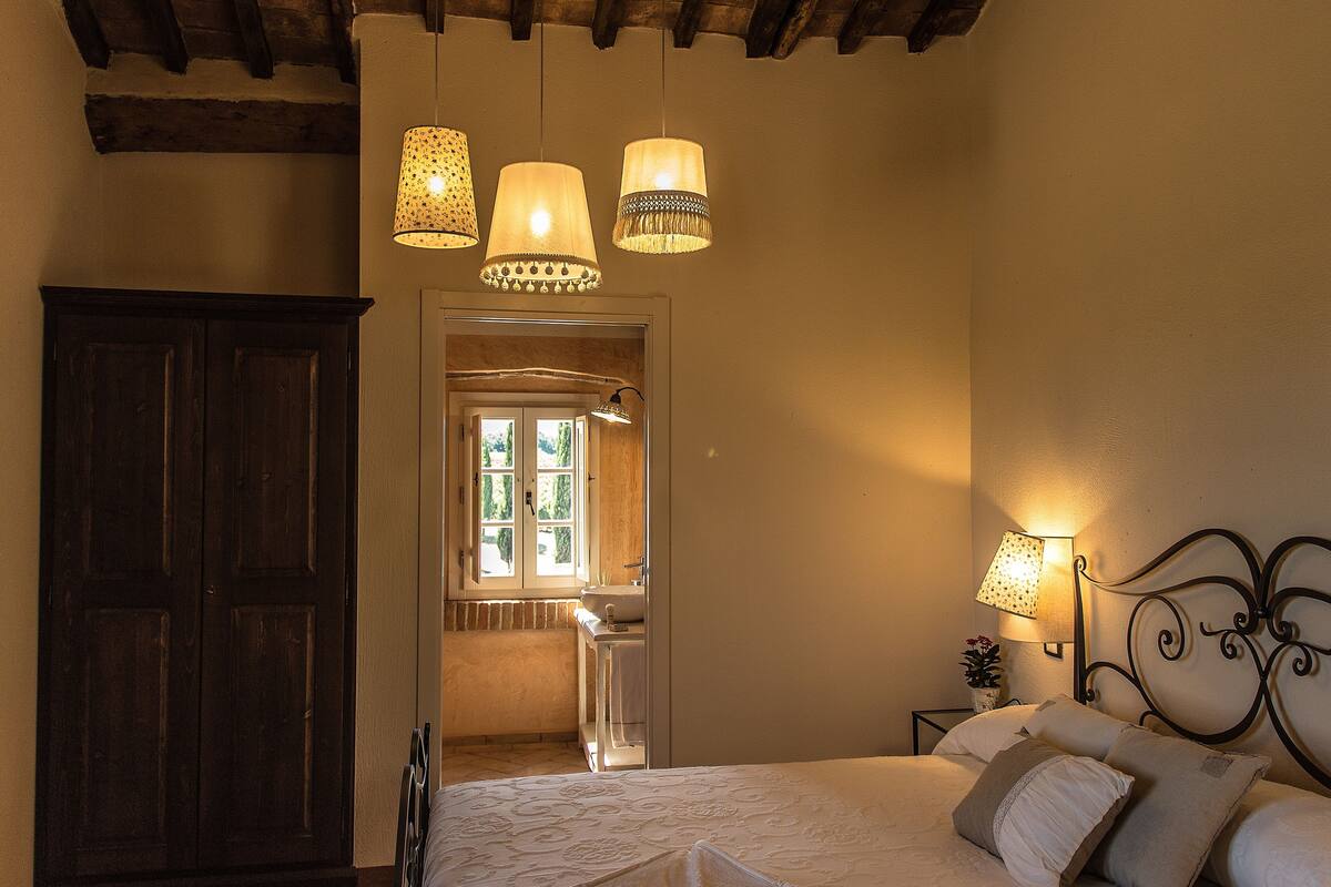 Ein Schlafzimmer mit einem Bett, Nachttischlampen, einem Holzschrank und einem Fenster mit Blick.