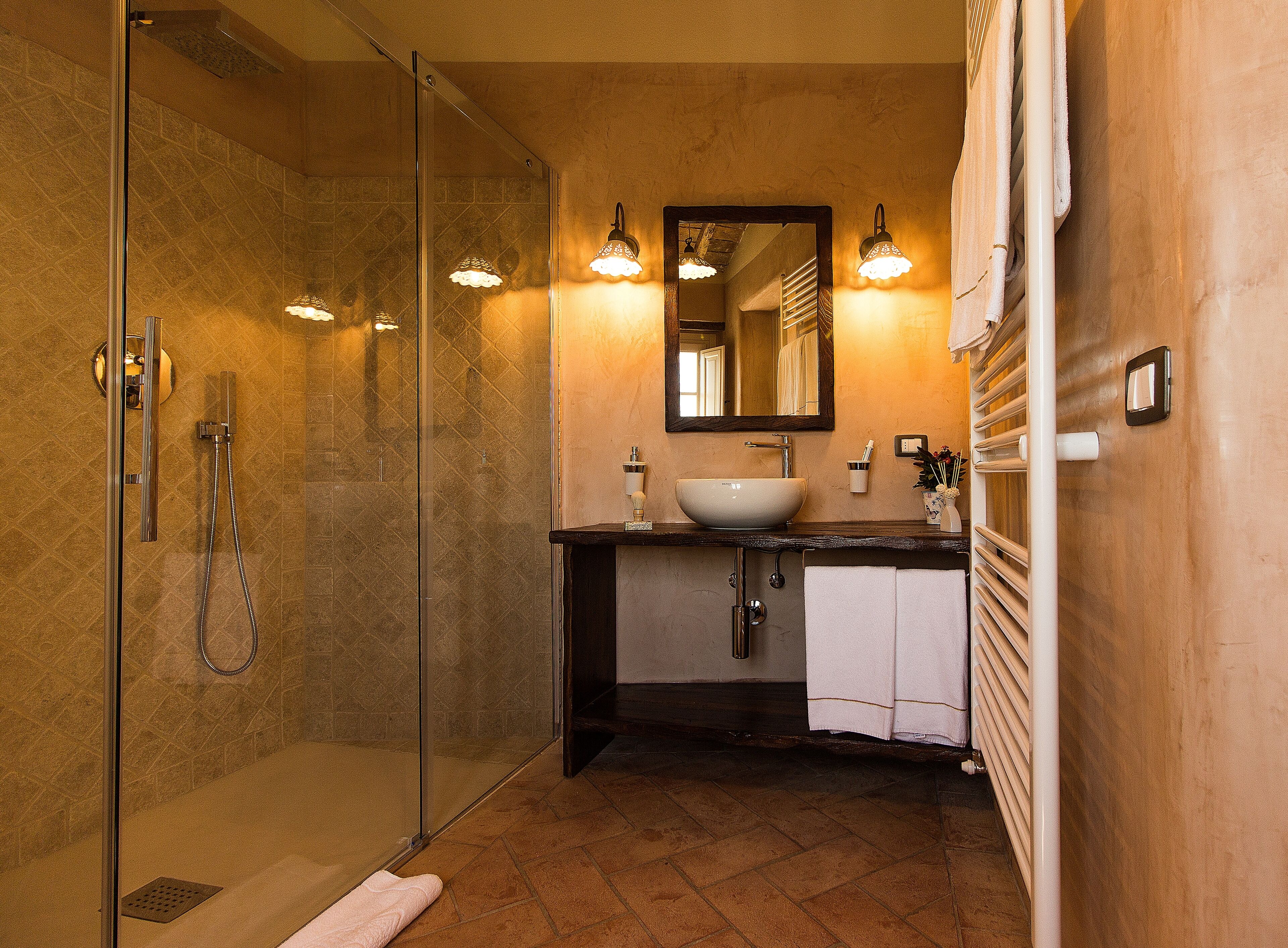 A bathroom with a glass-enclosed shower, a sink with a mirror above it, and a towel rack.
