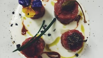 Un plato blanco con un guiso de comida, adornado con flores y bañado en salsa.