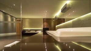 Una habitación de hotel moderna con una cama grande, un escritorio pequeño y una tocador con espejo.