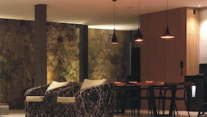 Un interior moderno con pared de piedra, mobiliario de mimbre, iluminación colgante y pared de paneles de madera.