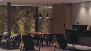 Un comedor moderno con pared de piedra, mesa de madera y sillas negras.