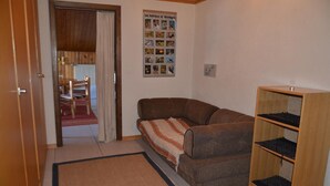A cozy room with a sofa, a bookshelf, and a poster on the wall. - Nice flat to rent in les Collons (Thyon-Les Collons)