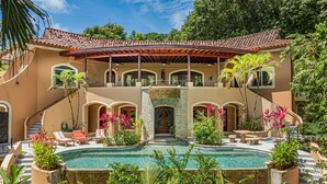 A two-story building with a swimming pool, outdoor seating, and lush greenery. - Casa Tranquilidad | Jungle Villa | Infinity Pool + Jacuzzi | Manuel Antonio (Manuel Antonio)