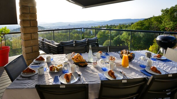 Mesa lista para el desayuno con vistas panorámicas, asientos al aire libre y una parrilla.