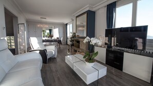 Una sala moderna con un sofá blanco, una mesa de centro de vidrio y un televisor.