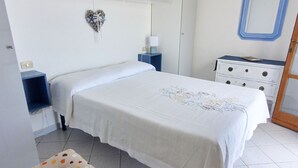 Een netjes ingerichte slaapkamer met een bed, nachtkastjes, een dressoir en een hartvormige decoratie aan de muur.