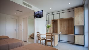 Una habitación de hotel moderna con dos camas, un escritorio y un televisor montado en la pared.