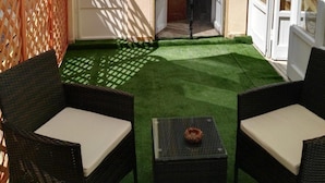 An outdoor seating area with wicker furniture and a table, a wooden lattice wall, and a door leading to another space. - B&B Main Street (Reggio Calabria)