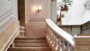 A grand staircase with a marble balustrade, leading to a landing with a wall-mounted light fixture. - B&B Main Street (Reggio Calabria)