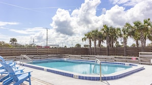 A swimming pool with blue tiles, surrounded by a wooden deck and palm trees. - Beautiful Oceanfront Penthouse ~ Incredible Views ~ Pool (Saint Augustine)