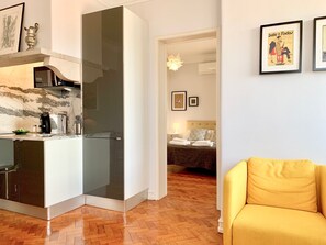 Um apartamento moderno com cozinha, sala de jantar, sala de estar com uma poltrona amarela e quarto com cama e mesa de cabeceira.