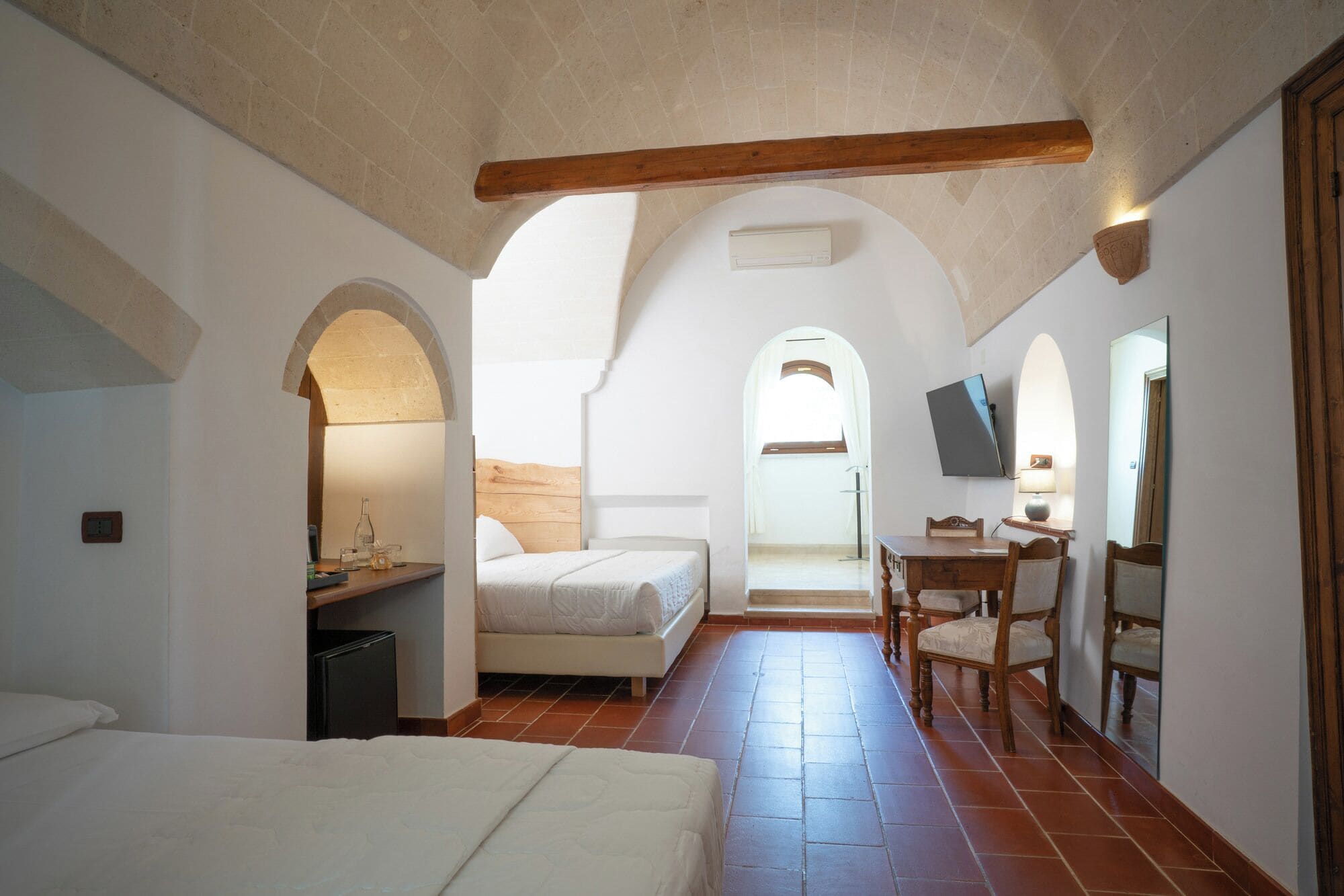 A bedroom with a bed, a desk, and a chair, connected by an arched hallway.