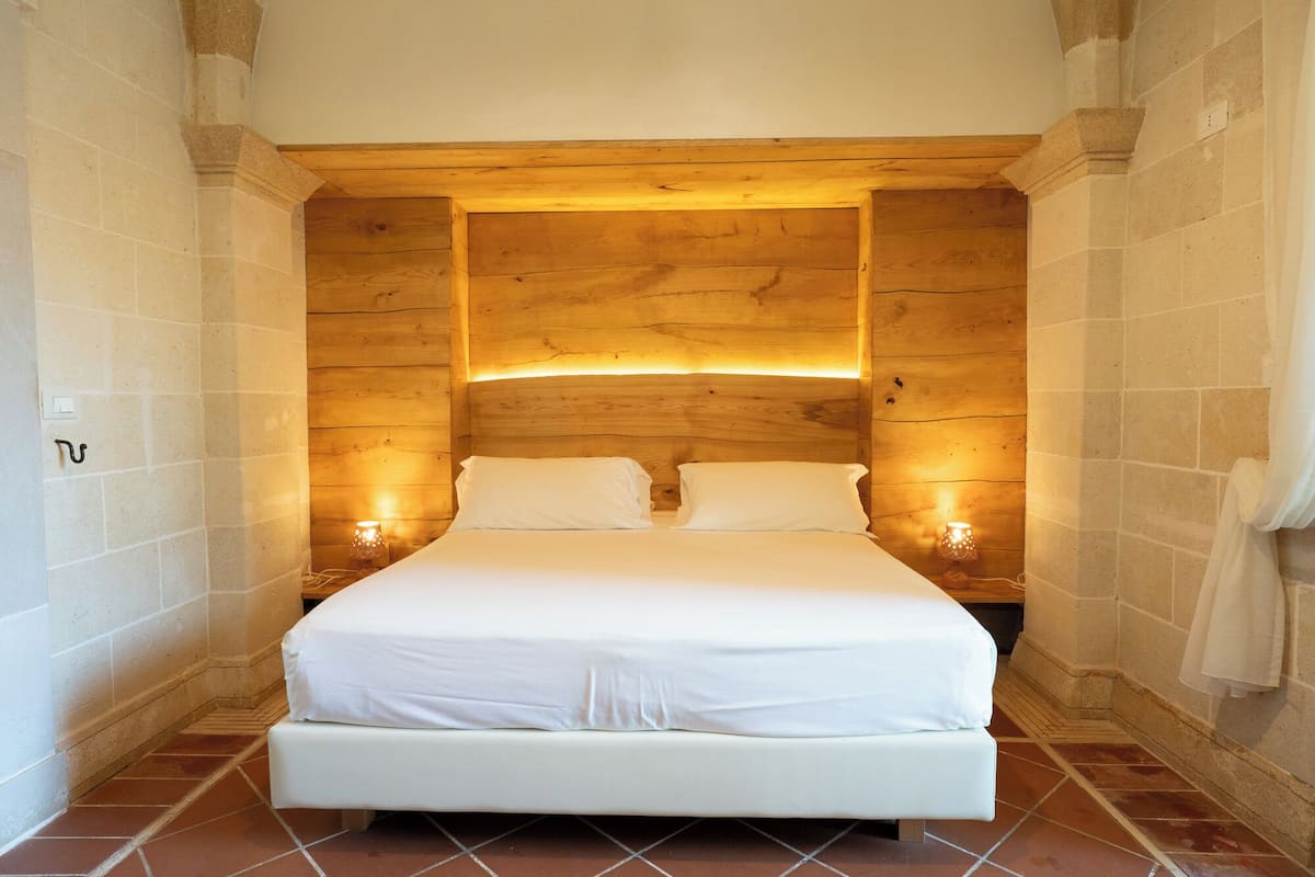 Ein Schlafzimmer mit einem hölzernen Kopfteil, zwei Nachttischlampen und einem weißen Bett.