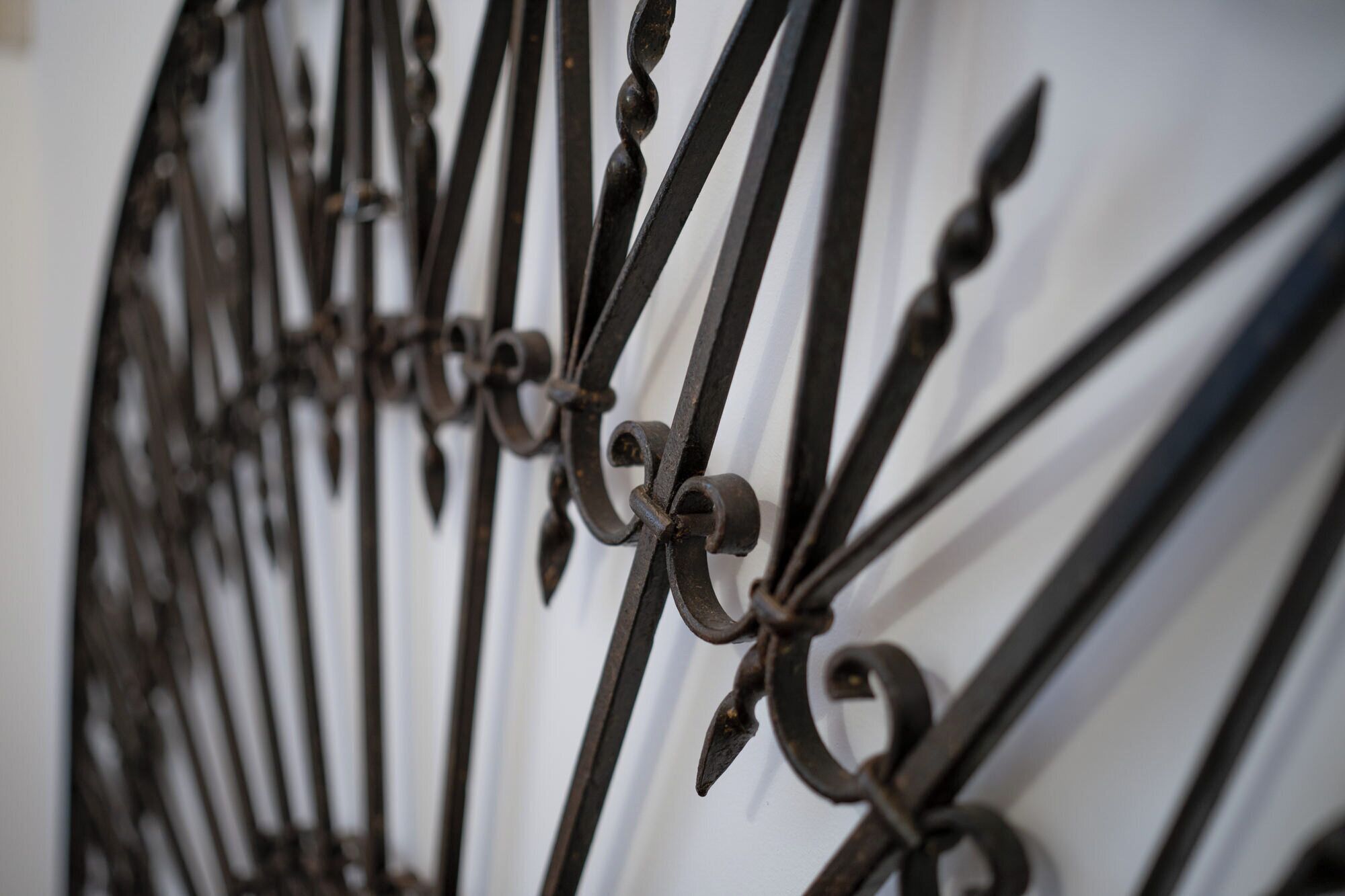 A close-up of a wrought iron gate with intricate scrollwork and a series of vertical bars.
