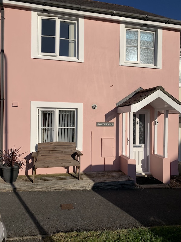 Un bâtiment rose avec un banc en bois, une porte et une enseigne sur laquelle on peut lire : « DAY DREAMS ».