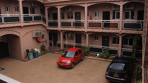 A multi-story building with a courtyard, featuring a red car parked in the center. - Hotel Exelle-Xior (Yaoundé)